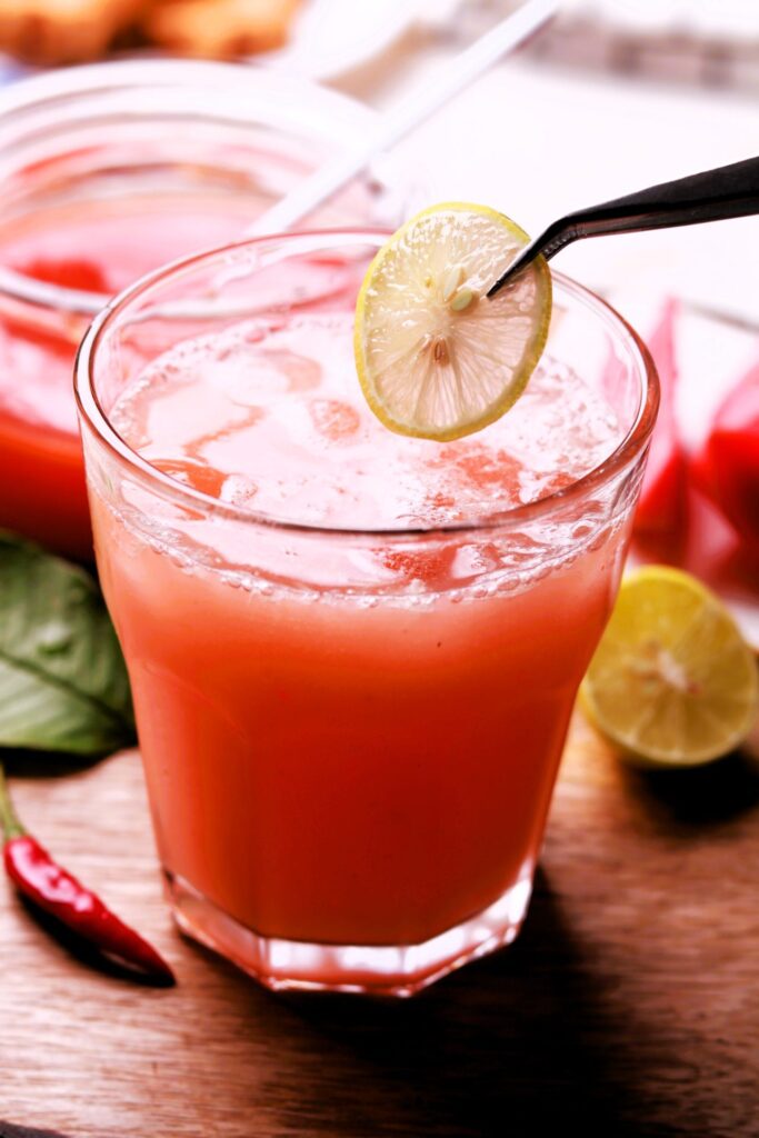 A refreshing guava-based beverage garnished with ice and lemon slice