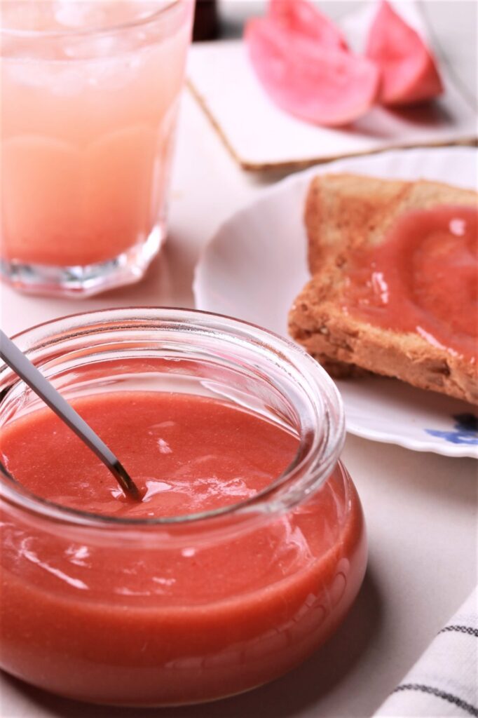 An enticing jar filled with homemade chili guava jam, showcasing its vibrant red-orange hue and tempting texture