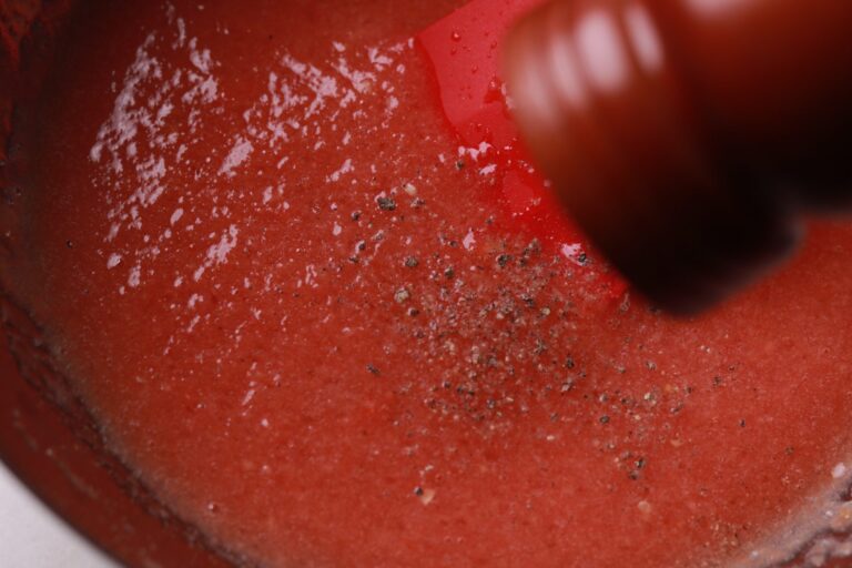 Sprinkling freshly ground black pepper into the guava pulp mixture