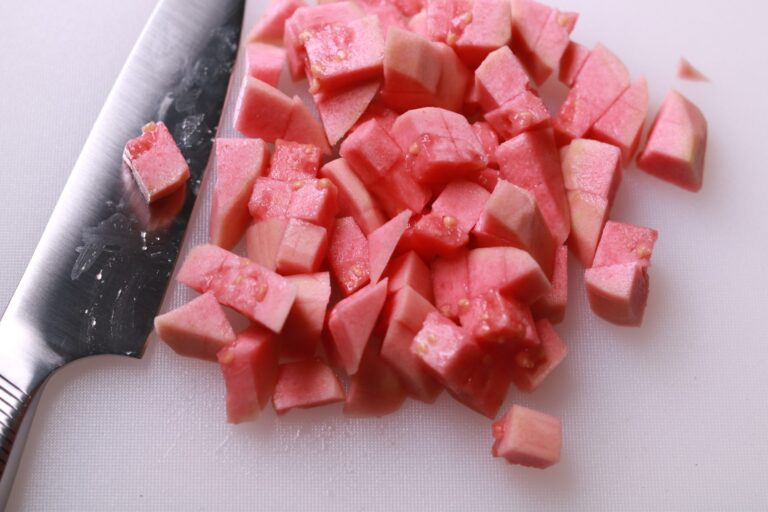 Hands skillfully dicing ripe guavas into neat cubes for jam preparation