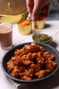 Sprinkling chat masala on the pakora