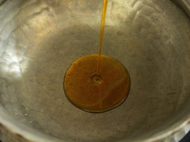 Pouring vegetable oil in sizzling pan for cooking delight.