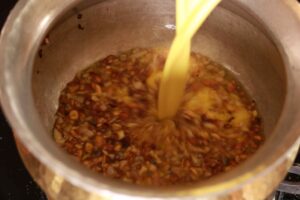Pouring besan mix into sizzling Kadai.