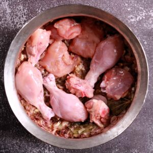 Chicken pieces in cooking vessel.