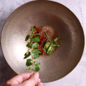 Sautéing chilies curry leaves for puliyogare recipe