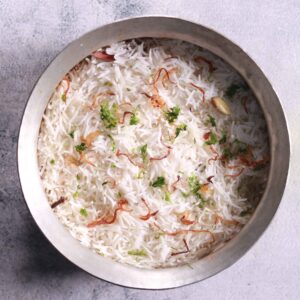 Garnishing Biryani with fried onions and coriander