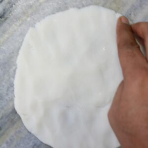 Hands flattening dough ball