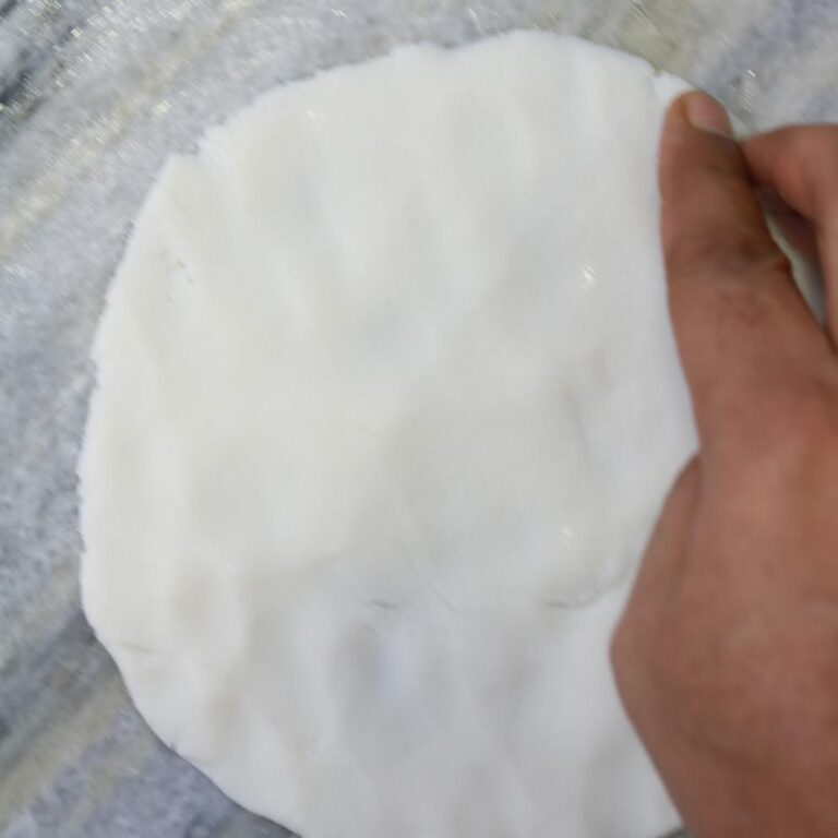Hands flattening dough ball
