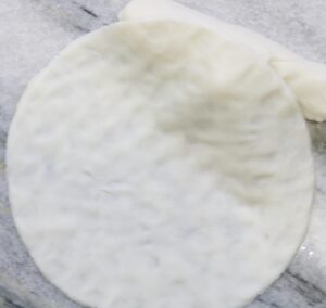 Hands shaping dough disc